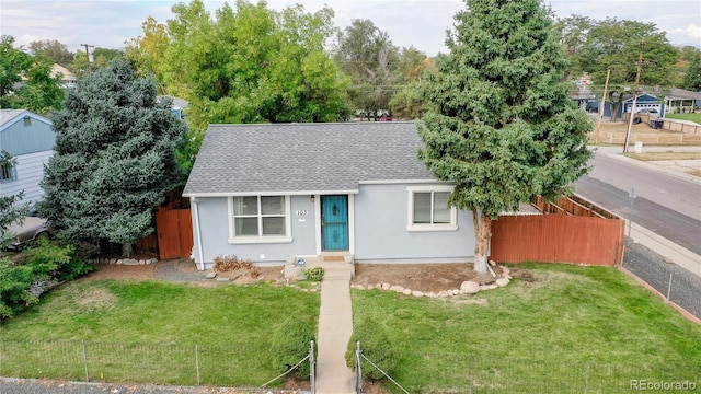 view of front of property with a shingled roof, a front yard, fence, and stucco siding