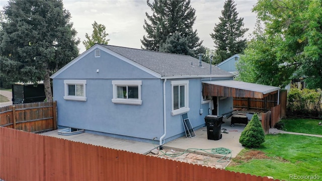 back of property featuring a patio, a shingled roof, fence, a yard, and stucco siding