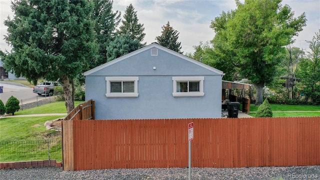 view of property exterior with fence, a lawn, and stucco siding