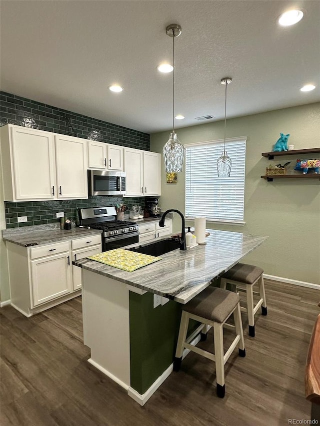 3974 Castle Vista Ln, Castle Rock, CO 80104 - kitchen with stainless steel appliances, decorative backsplash, a kitchen bar, dark wood-style flooring, and recessed lighting