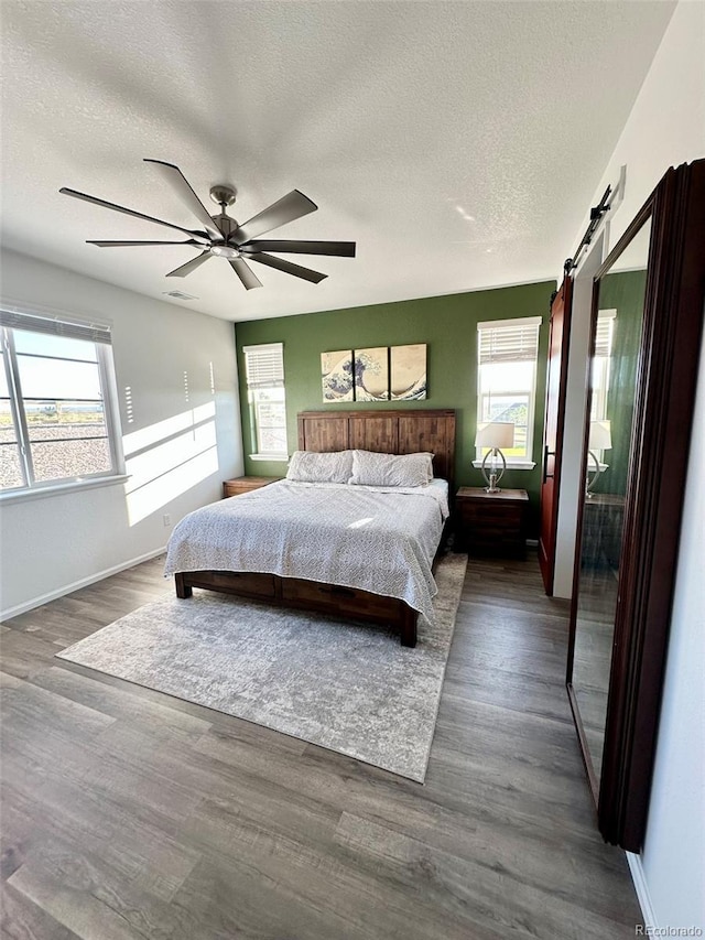 3974 Castle Vista Ln, Castle Rock, CO 80104 - bedroom featuring multiple windows, a textured ceiling, wood finished floors, a ceiling fan, and a barn door