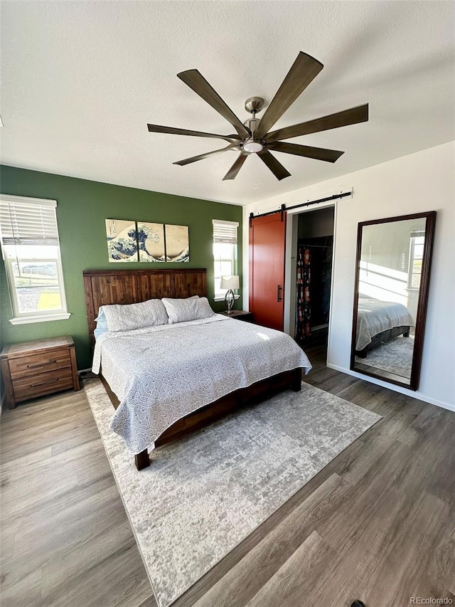 3974 Castle Vista Ln, Castle Rock, CO 80104 - bedroom featuring a barn door, wood finished floors, ceiling fan, and a textured ceiling