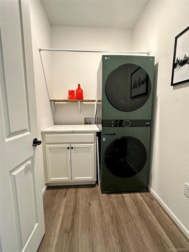 3974 Castle Vista Ln, Castle Rock, CO 80104 - laundry area featuring stacked washer / dryer, wood finished floors, and cabinet space