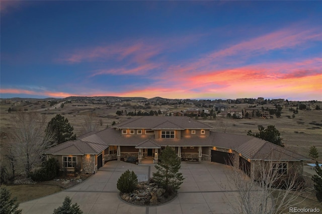 view of front facade featuring stone siding, concrete driveway, and a tiled roof