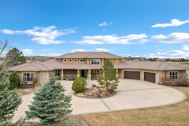 prairie-style home featuring a garage, stone siding, and a tile roof