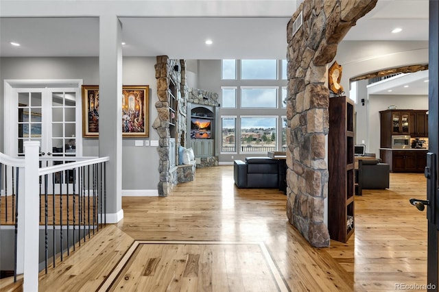 interior space with arched walkways, recessed lighting, baseboards, wood-type flooring, and ornate columns