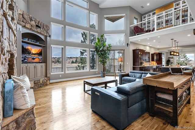 living room with light wood-style flooring, a high ceiling, and baseboards