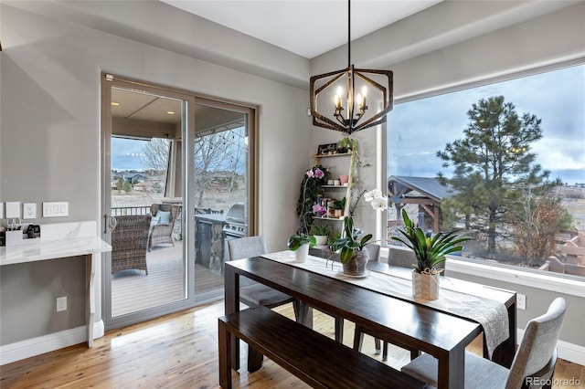 dining space with light wood-style floors, a chandelier, and baseboards