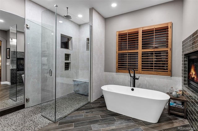 full bath with tile walls, a freestanding bath, a lit fireplace, and a shower stall