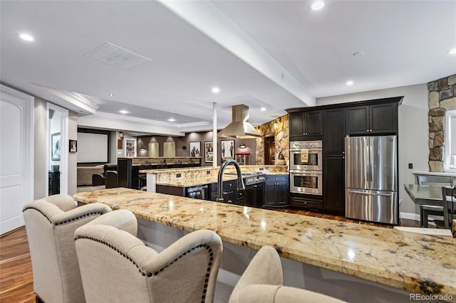 kitchen featuring appliances with stainless steel finishes, dark wood finished floors, light stone counters, and island range hood