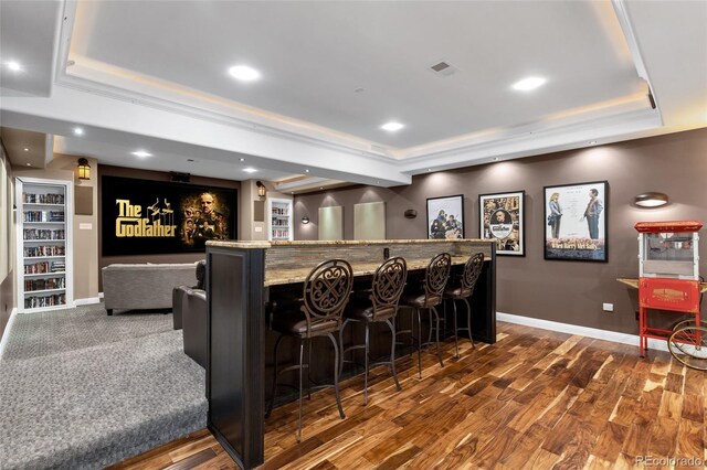 cinema room featuring dark wood-style floors, a dry bar, a raised ceiling, and visible vents