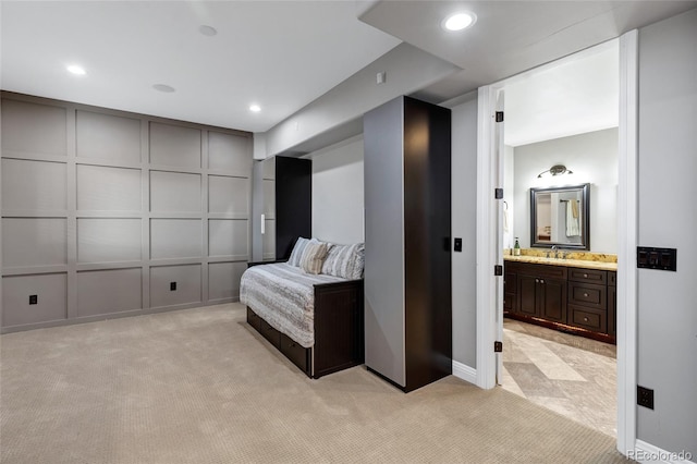 bedroom featuring light colored carpet, a decorative wall, and a sink