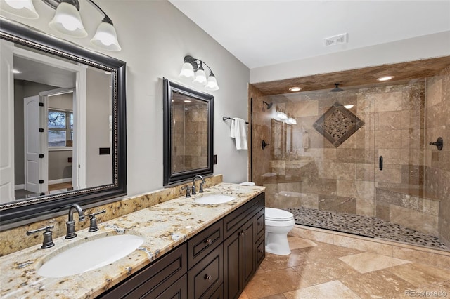 bathroom featuring toilet, a stall shower, visible vents, and a sink