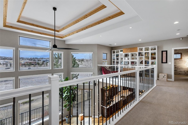 corridor featuring baseboards, carpet floors, a tray ceiling, and recessed lighting