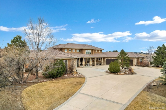 prairie-style house featuring driveway, an attached garage, a tile roof, and stucco siding