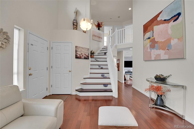 foyer entrance with hardwood / wood-style floors and a towering ceiling