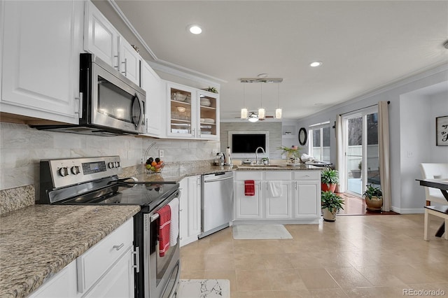 kitchen with pendant lighting, light stone countertops, ornamental molding, appliances with stainless steel finishes, and white cabinetry