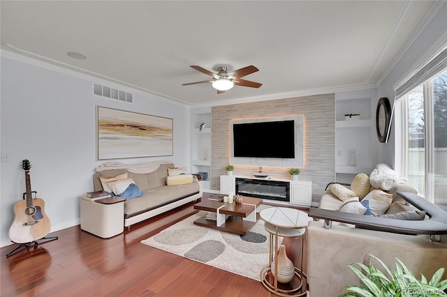 living room featuring a large fireplace, built in features, and ornamental molding