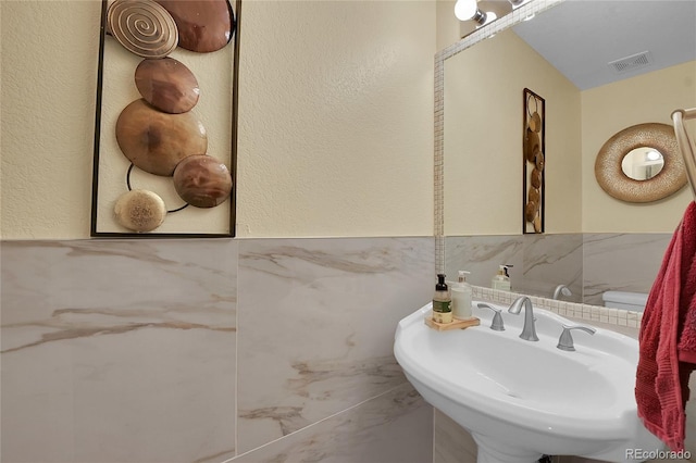 bathroom with sink and tile walls