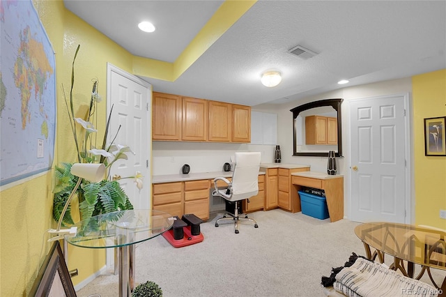 carpeted home office featuring built in desk and a textured ceiling