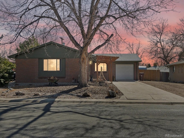 ranch-style house with brick siding, an attached garage, concrete driveway, and fence