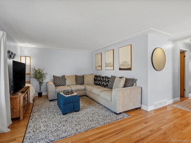 living room featuring wood finished floors, visible vents, and baseboards