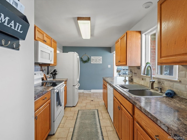 kitchen with dark countertops, tasteful backsplash, stone tile flooring, white appliances, and a sink