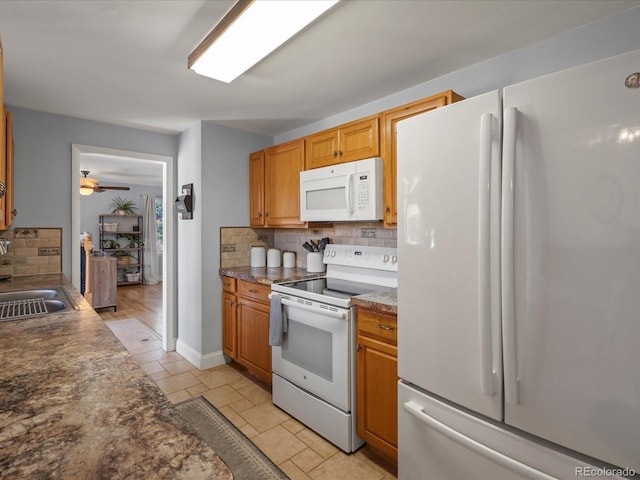 kitchen with a sink, white appliances, backsplash, and dark countertops