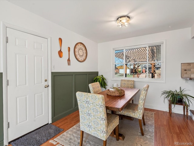 dining space featuring a wainscoted wall, a decorative wall, and light wood-type flooring