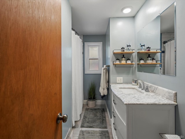 full bath featuring vanity, baseboards, and wood finished floors