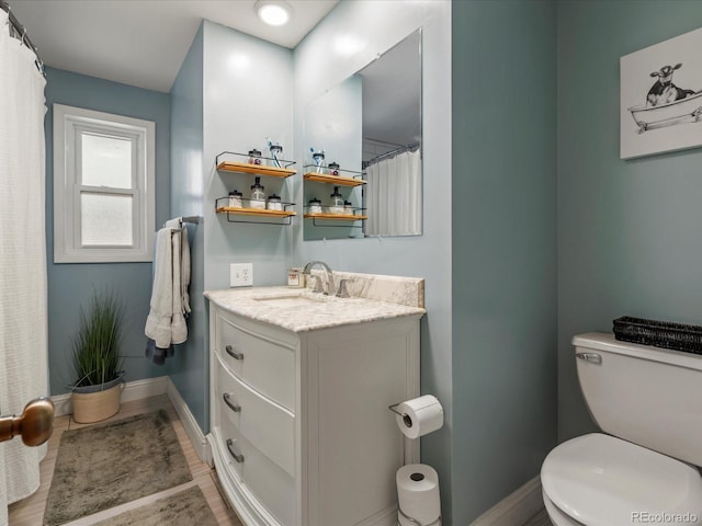 bathroom featuring baseboards, toilet, and vanity