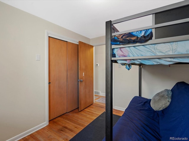 bedroom with visible vents, wood finished floors, and baseboards