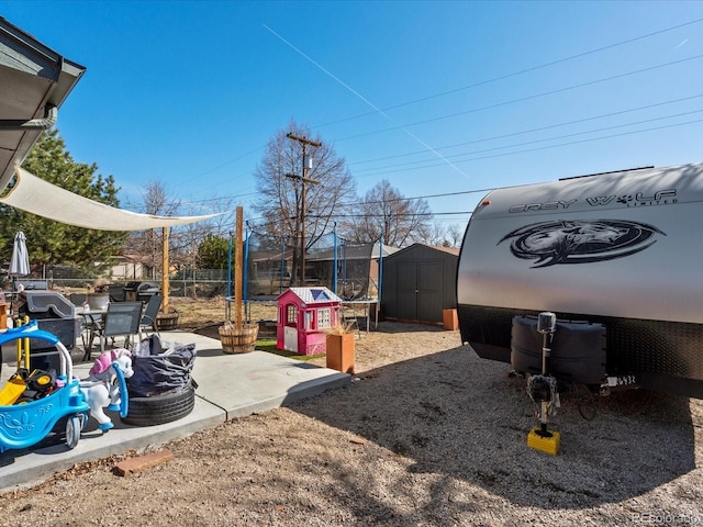 view of yard featuring a patio area, fence, an outbuilding, and a shed