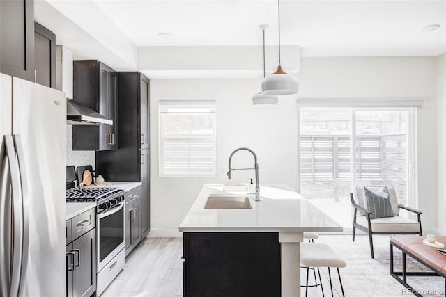 kitchen with sink, a breakfast bar area, decorative light fixtures, an island with sink, and stainless steel appliances