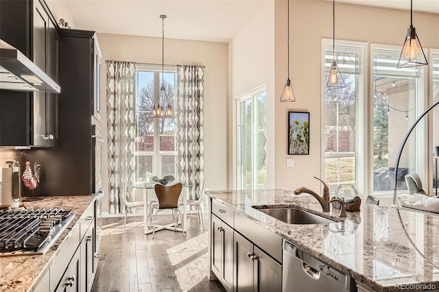 12114 Alcott St, Westminster, CO 80234 - kitchen with appliances with stainless steel finishes, wall chimney range hood, dark wood-style floors, light stone counters, and hanging light fixtures
