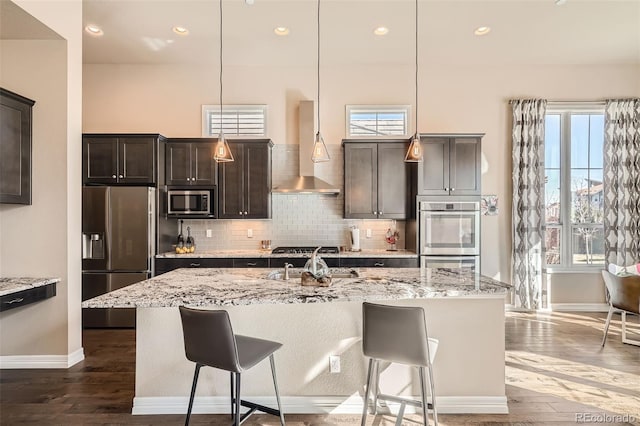12114 Alcott St, Westminster, CO 80234 - kitchen featuring appliances with stainless steel finishes, wall chimney exhaust hood, baseboards, a kitchen breakfast bar, and recessed lighting