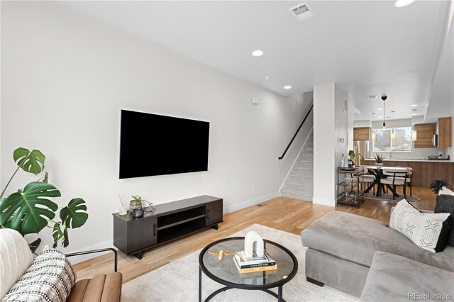 living area featuring recessed lighting, light wood-type flooring, stairs, and visible vents
