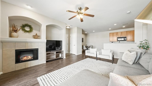 living room with dark hardwood / wood-style flooring, a fireplace, and ceiling fan