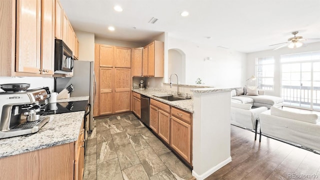 kitchen with sink, ceiling fan, appliances with stainless steel finishes, light stone countertops, and kitchen peninsula