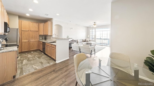 kitchen featuring sink, light stone counters, stainless steel dishwasher, dark hardwood / wood-style flooring, and kitchen peninsula