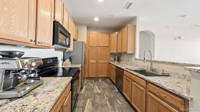 kitchen featuring light stone counters, sink, and black appliances