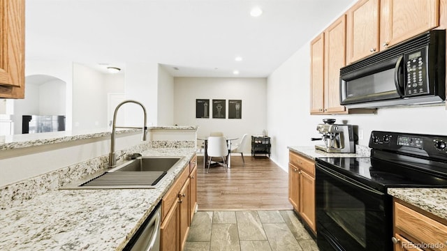 kitchen with light stone countertops, sink, light wood-type flooring, and black appliances