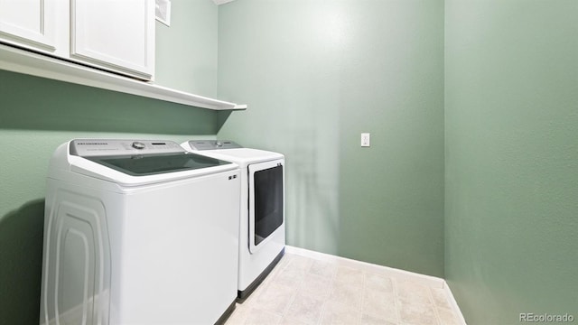 clothes washing area with cabinets and washing machine and dryer