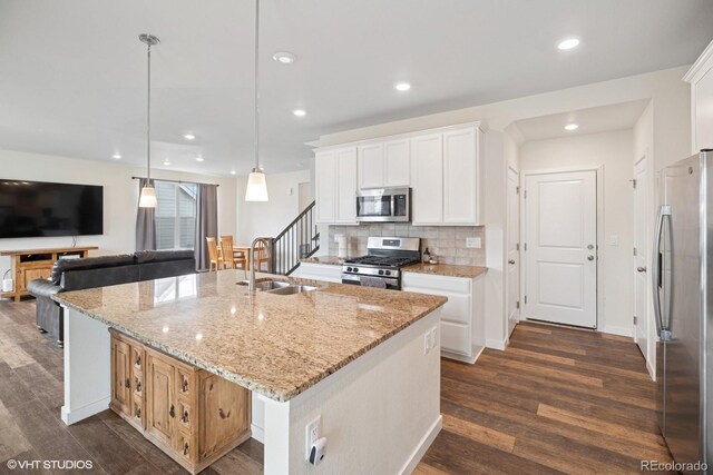 1143 Williams Loop, Elizabeth, CO 80107 - kitchen featuring appliances with stainless steel finishes, a kitchen island with sink, dark wood-style flooring, backsplash, and recessed lighting