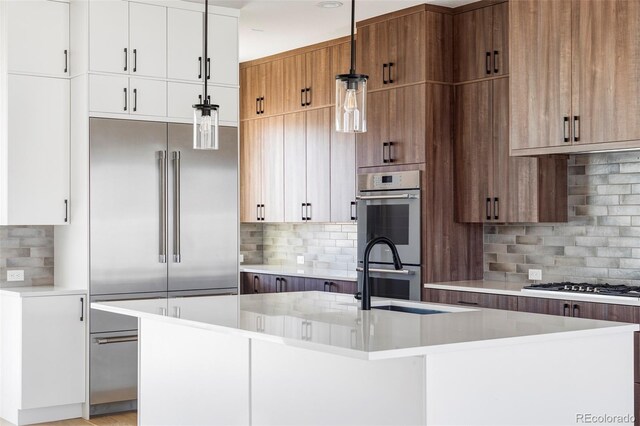 kitchen with pendant lighting, an island with sink, and white cabinets