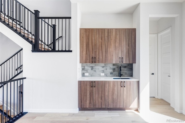 bar featuring tasteful backsplash, sink, and light wood-type flooring