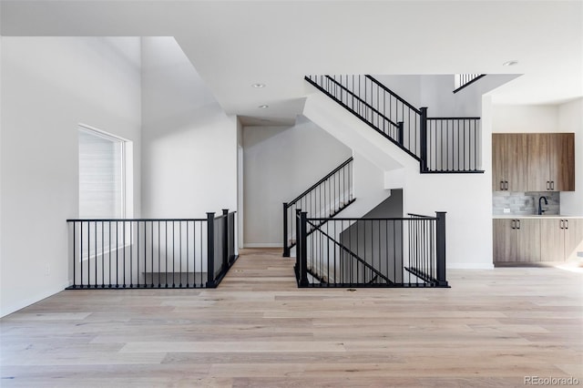 staircase with hardwood / wood-style flooring and sink