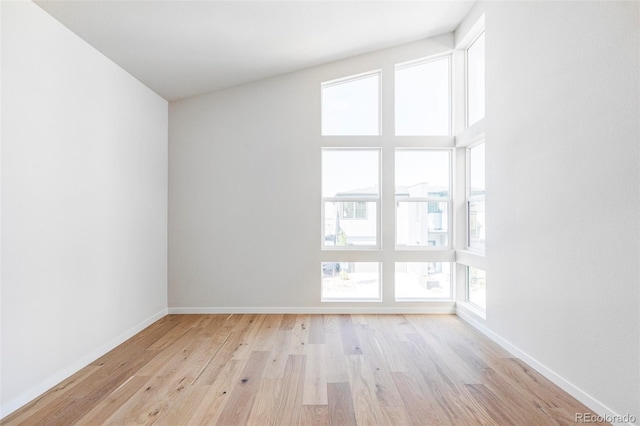 empty room with lofted ceiling and light hardwood / wood-style floors