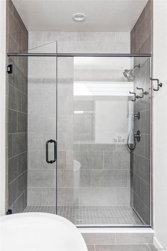 bathroom featuring a shower with shower door and a textured ceiling