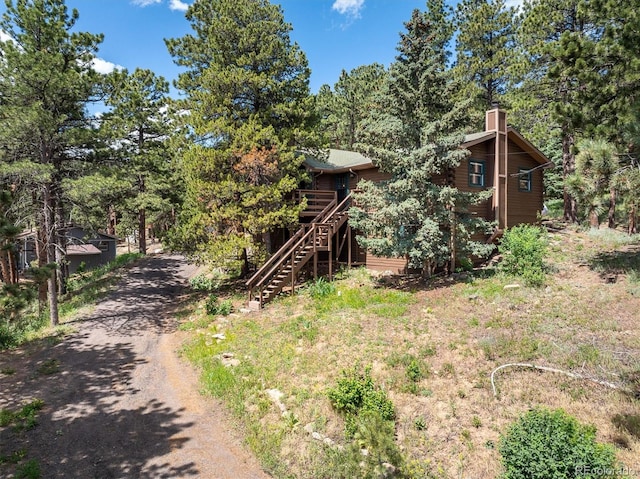 153 Divide View Dr, Golden, CO 80403 - rustic home with driveway, stairs, a chimney, and a wooden deck